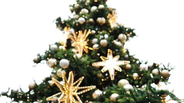 Close up of an outdoor Christmas tree adorned with shiny gold and silver baubles and glowing lights on a historic European city square.