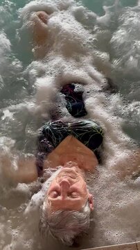Femme &acirc;g&eacute;e dans un bain &agrave; remous