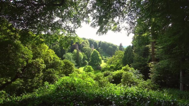 Scenic framed shot looking down into the lush rolling valley garden of Stourhead estate in Wiltshire, England, with a classical temple structure visible on the distant hill on 27.08.2024