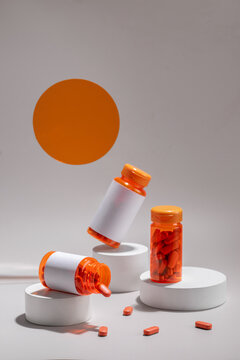 Orange pill bottles and scattered capsules on a minimalist setting