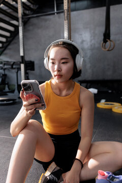 Woman with headphones using mobile phone at the gym.