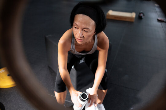 Woman rests with water bottle after workout.
