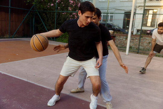 three young men are playing basketball