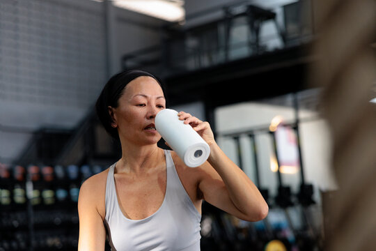 Woman drinks from water bottle at the gym.