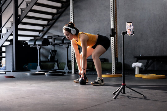 Woman recording kettlebell workout in gym