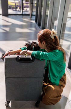 Woman and Chihuahua dog share tender moment in travel carrier.