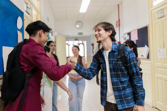 Diverse students greeting each other discussing walking school hallway