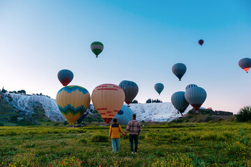 Fototapeta premium Hot air balloons drifting over the stunning travertine terraces of Pamukkale, Turkey