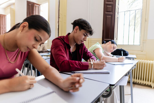 Students taking exam in a classroom, writing notes