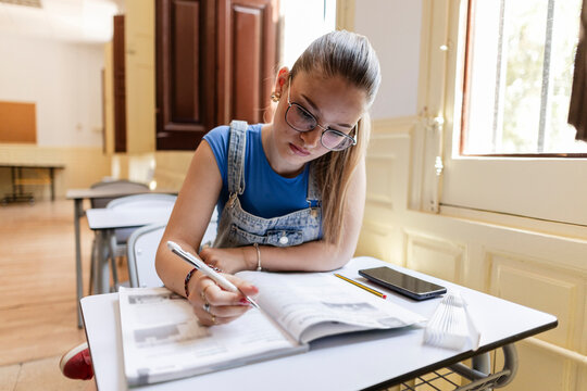 Female student concentrating on studying in school classroom