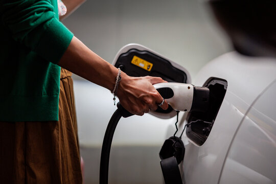 Driver connecting electric vehicle charging cable to car