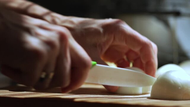  Hands Slicing Fresh Onion Slow Motion. Close up of hands slicing fresh white onion with a kitchen knife on a wooden cutting board in slow motion.