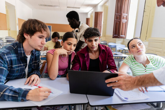 Diverse students collaborating on digital learning in classroom