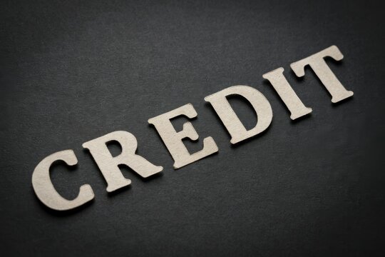 The word "CREDIT" made of wooden letters on a black background