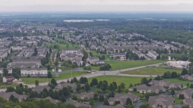 Drone aerial above city of Hilliard, Ohio suburban landscape as a suburb outside Columbus, OH with townhomes, residential units, duplex homes, houses, and rental buildings in middle class neighborhood