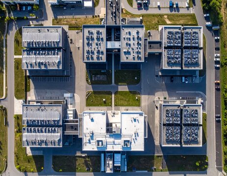 Vertical top-down aerial view of a large modern data centre campus, featuring symmetrical buildings, precise geometry, access roads and organized infrastructure.