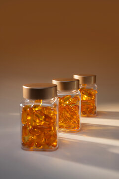 Three clear bottles filled with golden omega-3 fish oil capsules