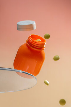 Orange pill bottle with cap off and pills scattered on clear surfaces