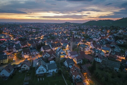City view at dusk with illuminated houses and a church under a picturesque evening sky, Korb im Rems Valley, Baden-W&uuml;rttemberg, Germany