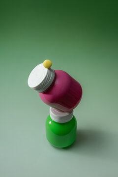 Two colorful plastic bottles stacked with a yellow sphere on green
