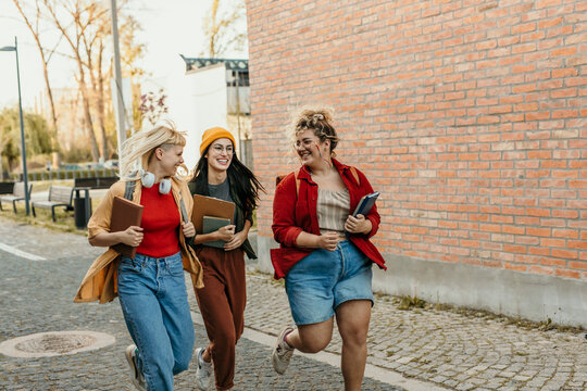 Diverse students running on campus, enjoying university life