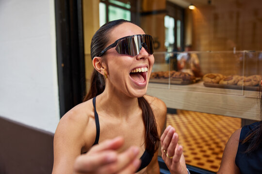 Woman smiles while sitting at cafe in city during daylight hours
