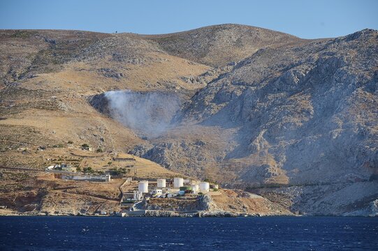 Waste incineration plant, tanks, dry mountain landscape with industrial plant and blue sea in the foreground, Pothia, main town, port, Kalymnos, Sponge Diving Island, Dodecanese, Greek Islands, Greece