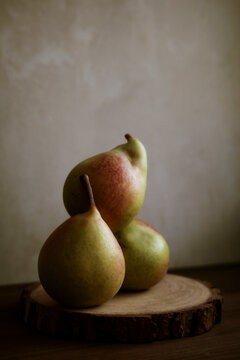 Three Pears Arranged on a Wooden Slice in Soft Light