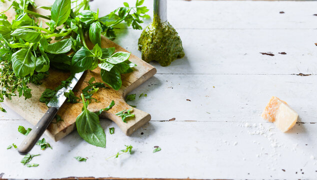 Fresh pesto preparation on a wooden cutting board with herbs