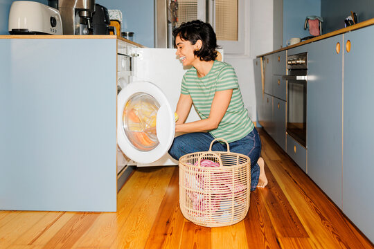 Woman doing laundry at home using washing machine ugc
