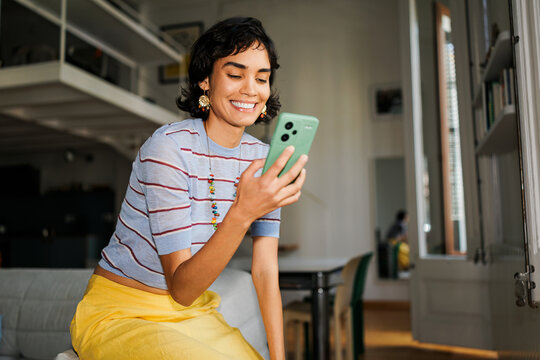 Smiling woman using mobile phone connecting online home ugc
