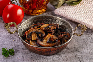 Fototapeta premium Sauteed mushrooms in a traditional copper pan with fresh tomatoes and herbs