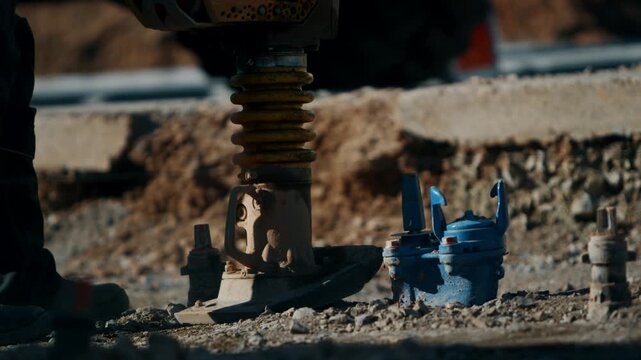 Vibratory rammer compacting gravel ballast on railway track