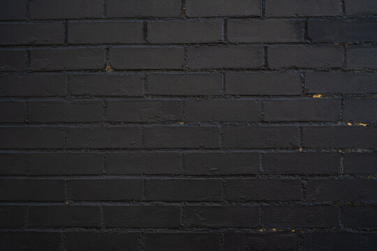 Dark grey painted brick wall texture background with subtle wear and exposed orange brick