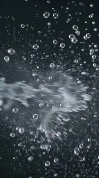 Dynamic splash of clear water with many bubbles against a dark background.