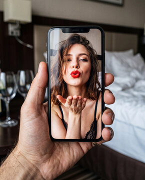 ホテルでのビデオ通話、スマホ越しに投げキスをする魅惑的な女性