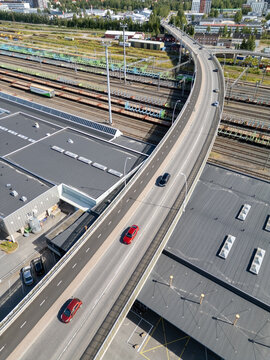 Oulu, North Ostrobothnia, Finland - 05 August 2026: Aerial view of a curved road bridge crossing over extensive railway tracks and industrial buildings in the city center.