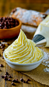 A bowl of whipped cream with chocolate chips on a wooden table
