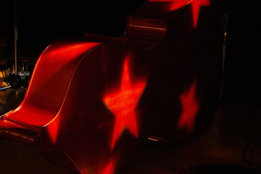 upright string bass resting on a stage with star stage lighting