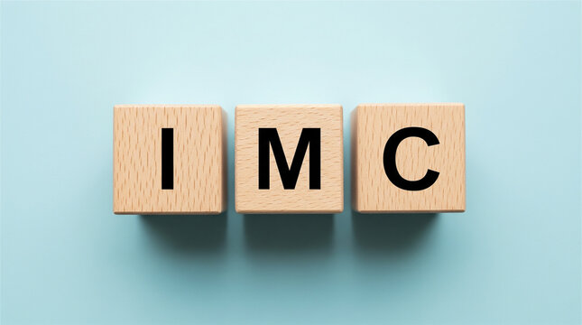 Wooden cubes displaying the acronym IMC lie on a light blue background.