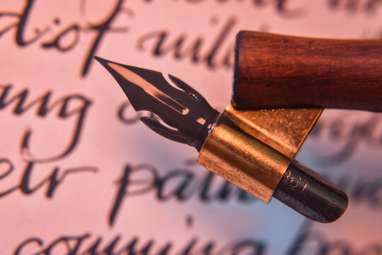 Old calligraphy pen closeup over the handwriting