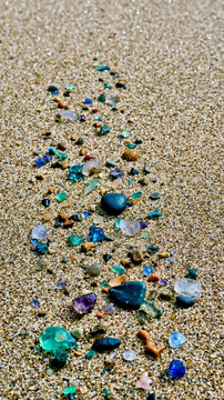 A beach with a variety of colorful rocks and pebbles scattered across the sand