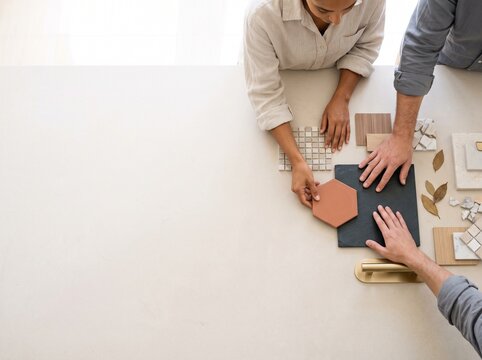 Top view of interior designers selecting tiles, wood, and stone material samples on a table with copy space
