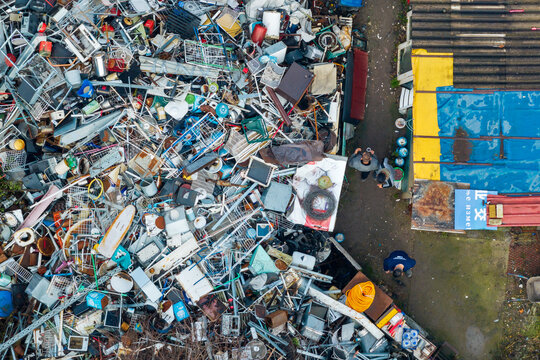 Zemun, Serbia - 18 December 2025: Aerial view of recyclable materials collectors working in a scrap yard with piles of metal and plastic waste.