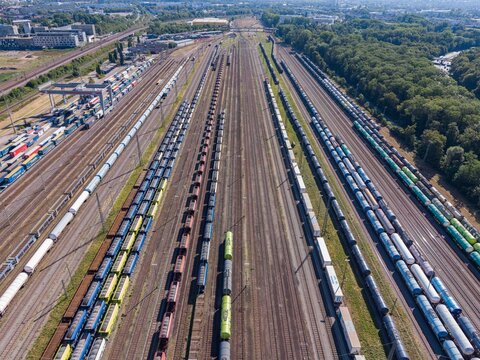 Karlsruhe, Germany - 29 July 2026: Aerial view of a large railway marshalling yard with numerous freight trains and cargo containers on parallel tracks.
