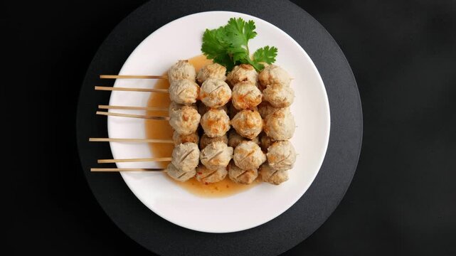 Charcoal grilled Thai Pork meatballs on skewers on white plate