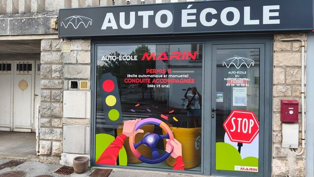 Royan, France - July 15, 2026: Charente-Maritime. Nouvelle-Aquitaine. Auto ecole Marin driving school storefront with colorful signage, steering wheel graphic, and stop sign displayed prominently