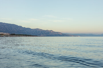 Obraz premium Albania, Velipoja 12 09 2025: Wide late afternoon photo of sea water with distant Mali-Shengjin mountain ridge and blue sky on coastal horizon at Velipoja beach.