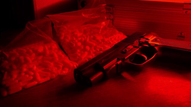 Drug Pills In Bags With Gun In Red Light