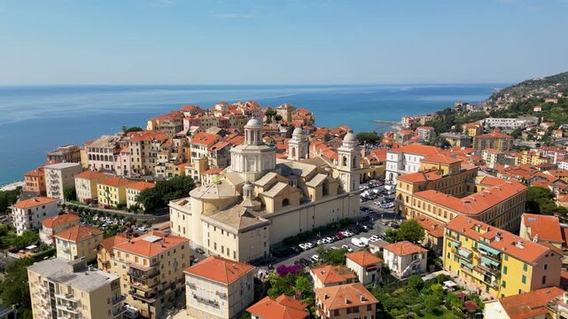Aerial drone footage of Porto Maurizio historic quarter in Imperia featuring colourful houses perched on promontory and San Maurizio Cathedral on sunny day in Liguria Italy
